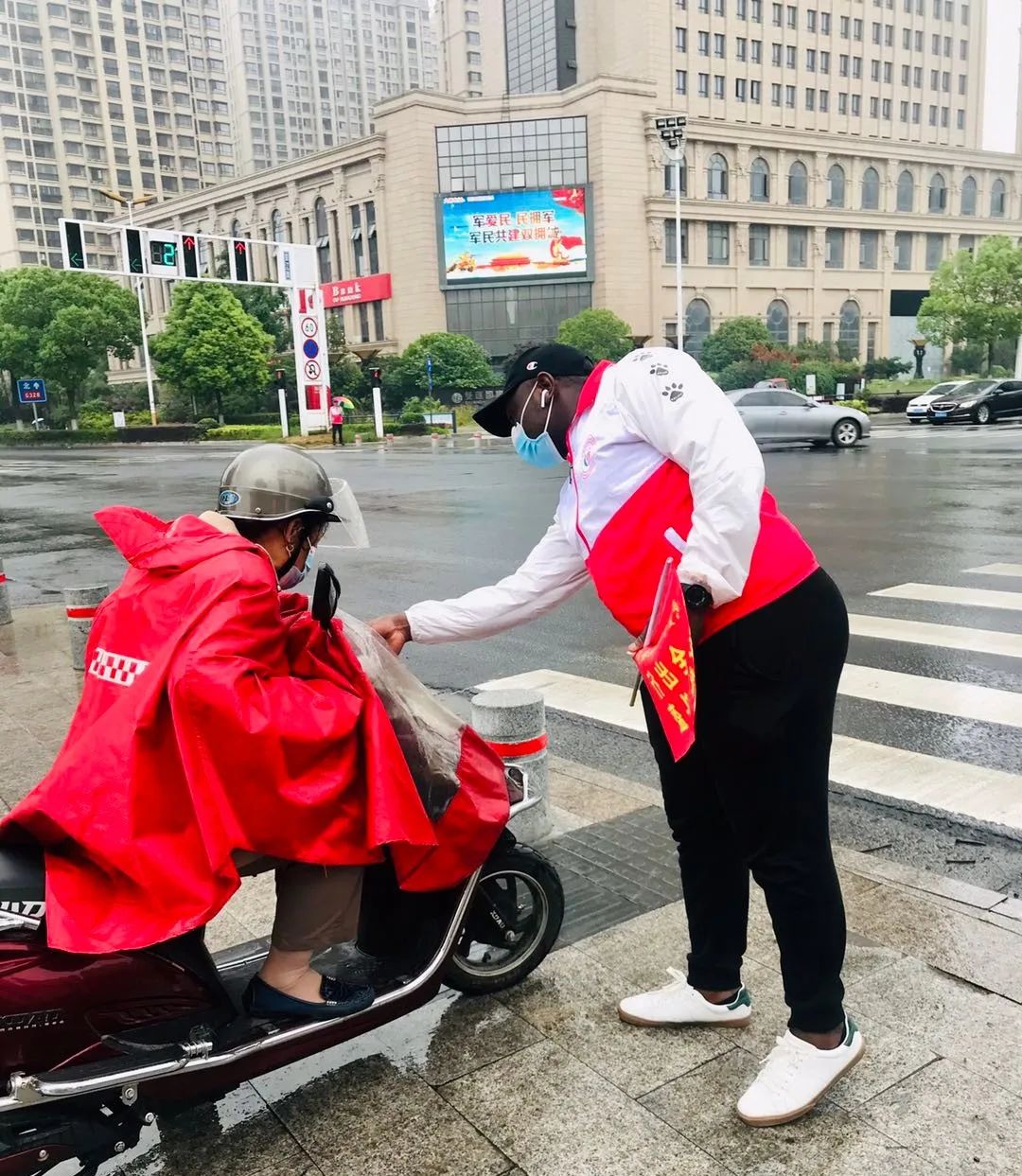 啥情况?江都街头有个黑人小哥,穿着红白相间的马甲,举起小红旗